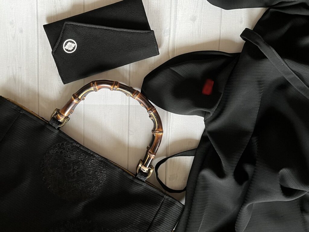 着物の喪服からリメイクされた竹のハンドルのバッグと家紋が入った数珠入れとポケットの裏には着物に付いていた名前部分を残したワンピース